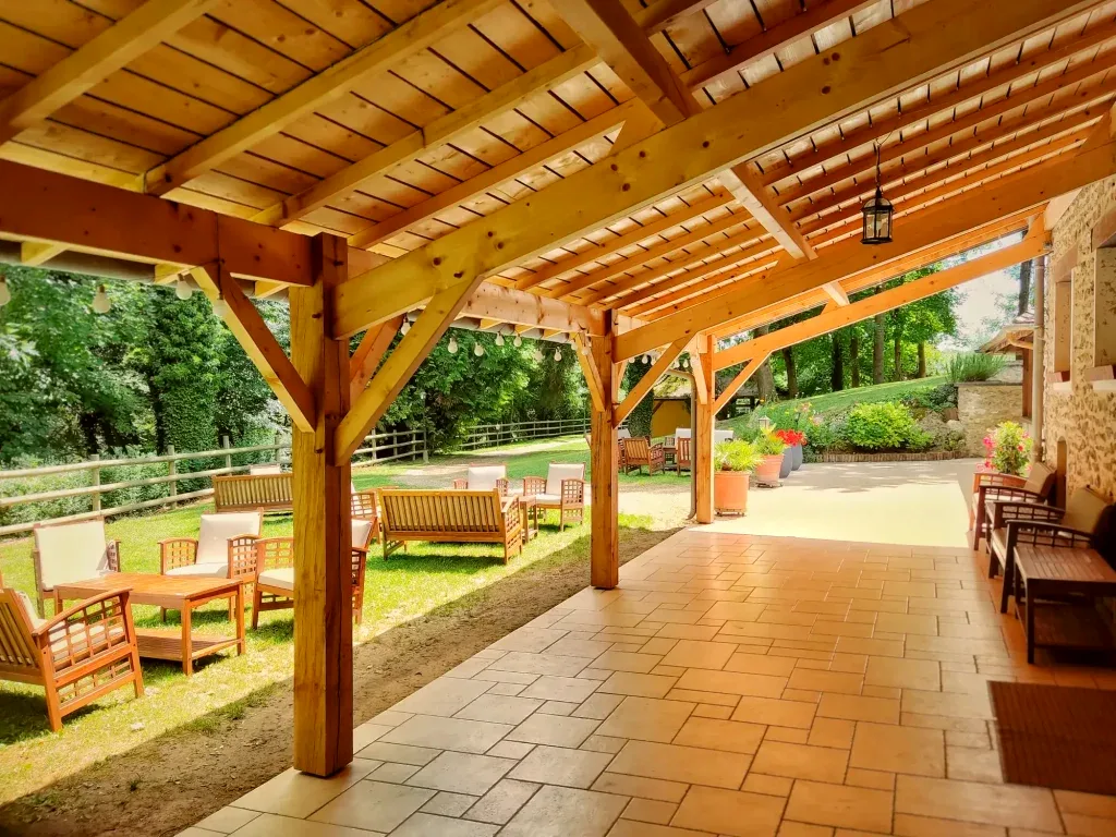 Préau en charpente de bois et terrasse couverte du Domaine du Moulin Bicheret