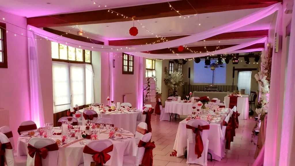Salle de réception du Moulin Bicheret en éclairage d'ambiance bordeaux pour une soirée dansante
