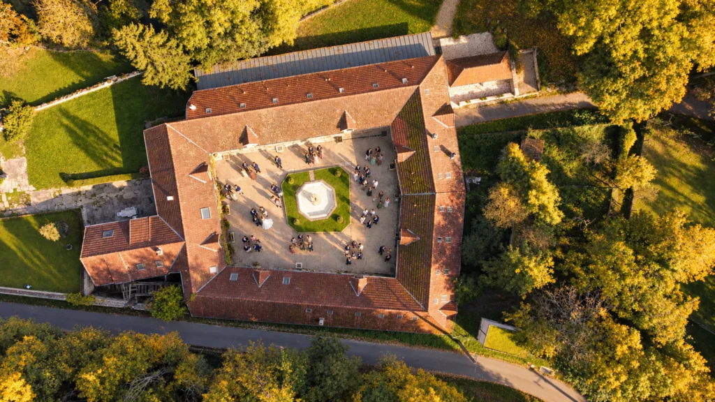 Vue aérienne du Domaine du Moulin Bicheret : bâtiments autour de la cour intérieure et de sa fontaine, entourés d'un parc arboré